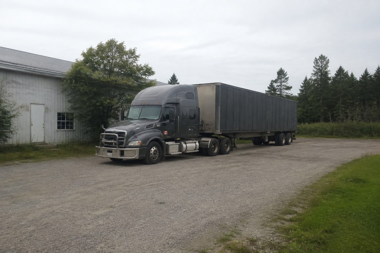 A parked tractor-trailer in a quiet Canadian summer yard